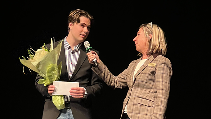 Bild på två personer i intervjusituation på en scen med svart bakgrund. En person har mikrofon. Den andra håller i en blombukett. Bild på två personer i intervjusituation på en scen med svart bakgrund. En person har mikrofon. Den andra håller i en blombukett.